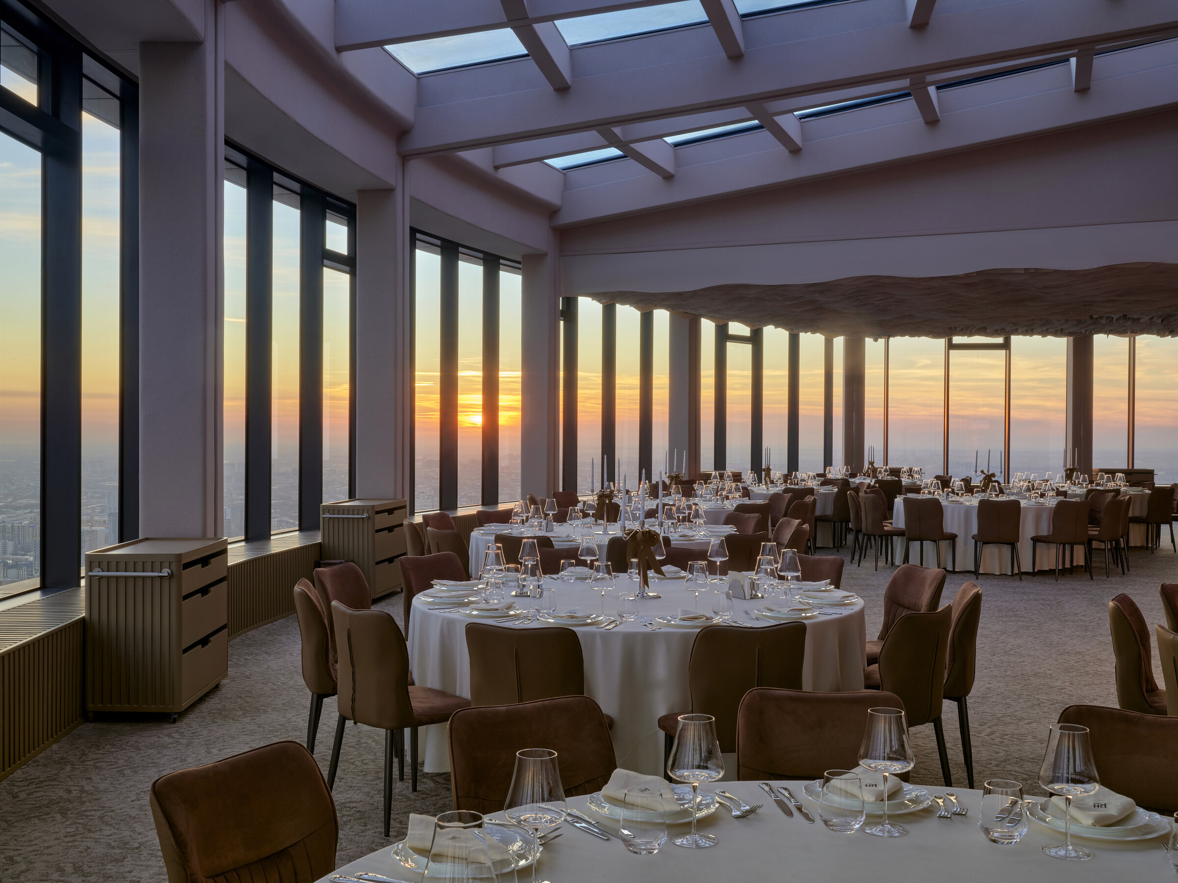 Rooftop Hall at golden hour — crystal glasses and candelabra against the Tashkent sky, 48th floor