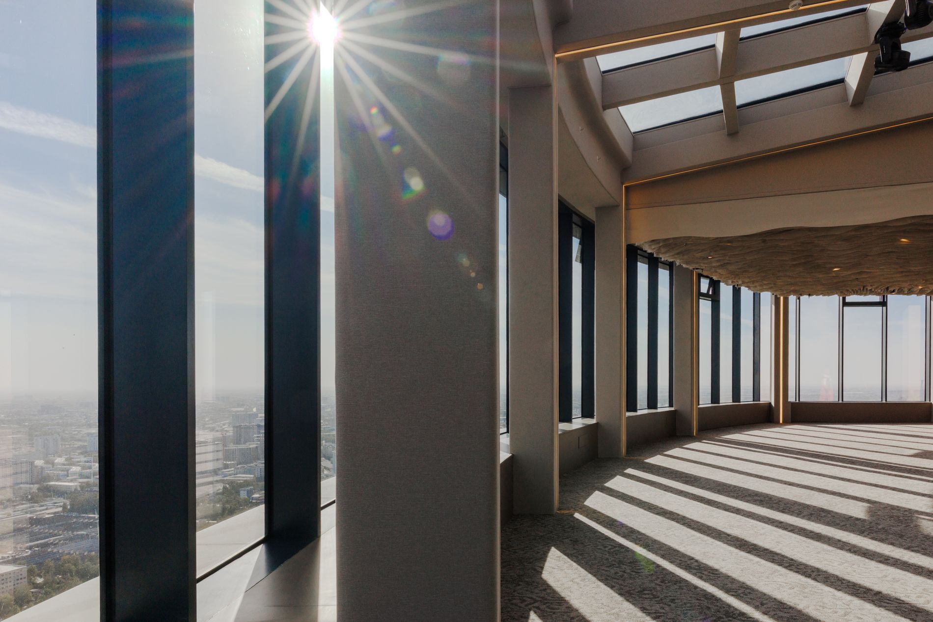 Rooftop Hall — architectural detail, sunlight through floor-to-ceiling columns over the city