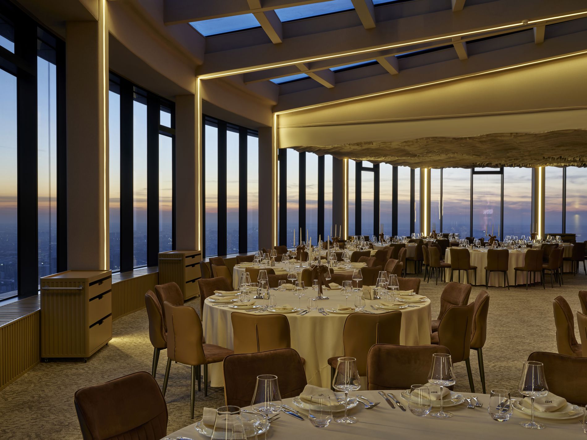 Rooftop Hall — banquet tables set for an evening event at dusk, panoramic skyline beyond