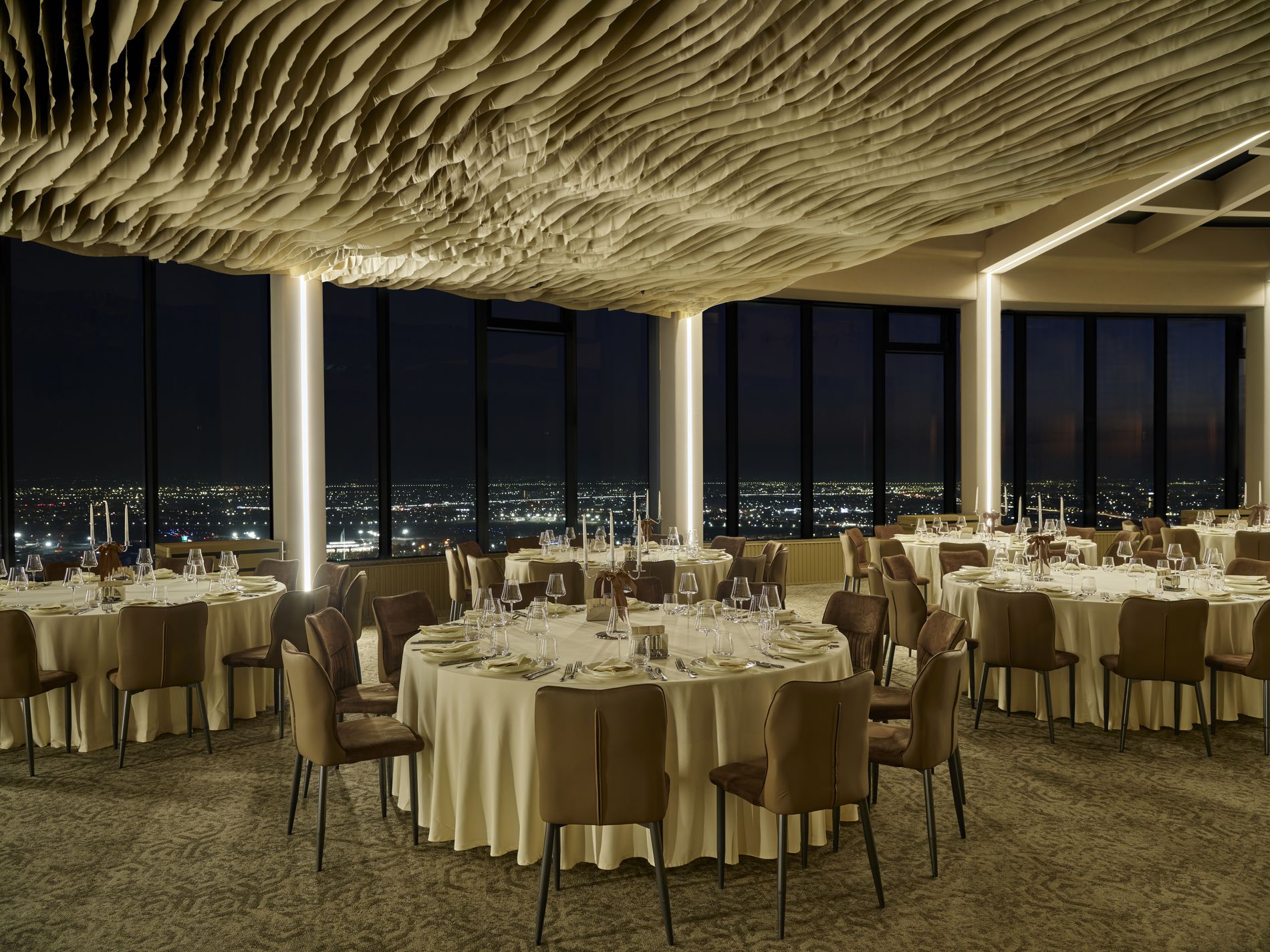 Rooftop Hall — the hall at night, dramatic ceiling detail above tables set beneath the city lights