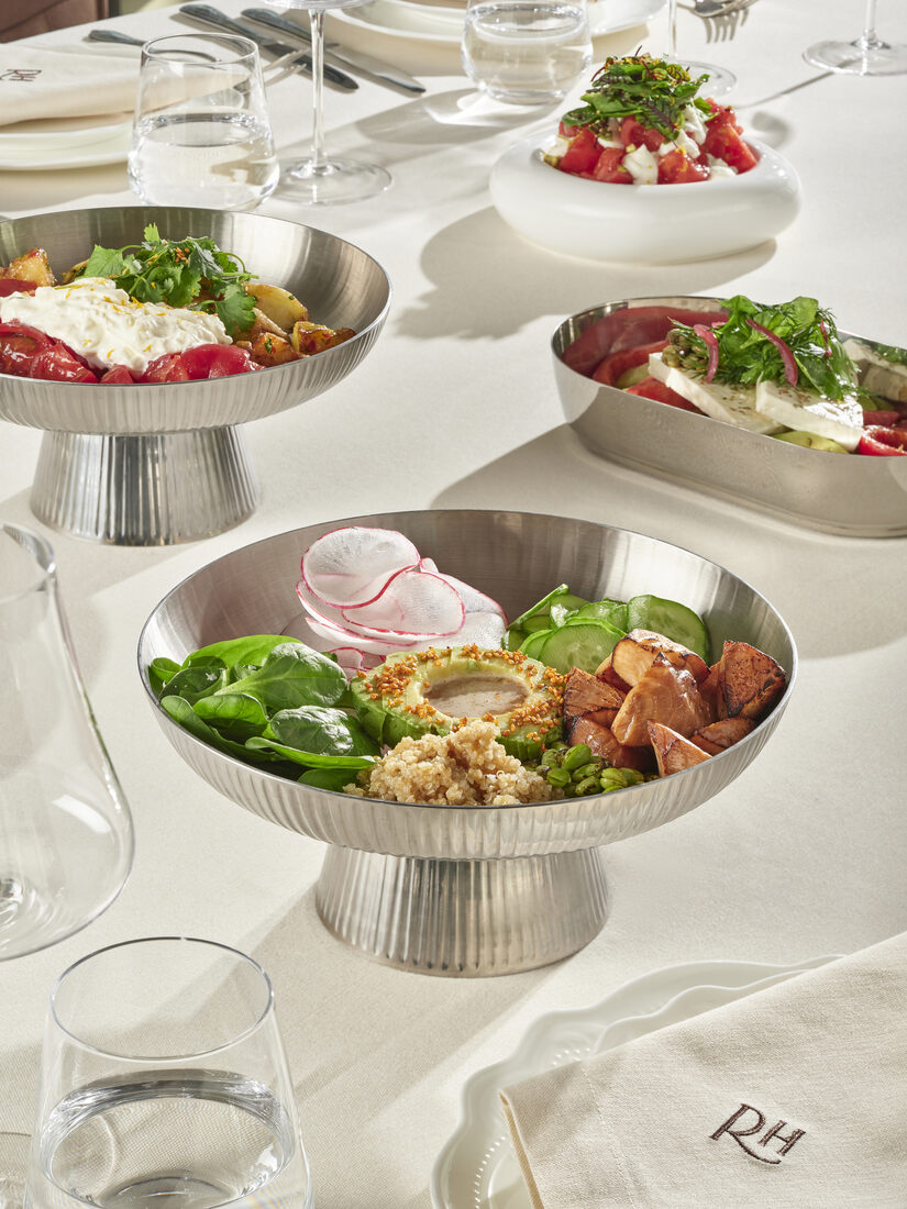Table scene — multiple dishes, RH monogram napkin, silver serveware